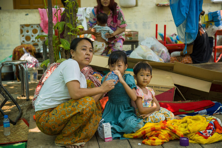 A woman kneels next to her children at a shelter in Myanmar